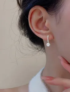 Gros plan détaillé de boucles d'oreilles pendantes en zircon rond portées par un modèle