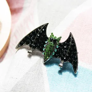 Detailed macro shot of a retro bat brooch featuring black and green sparkling rhinestones