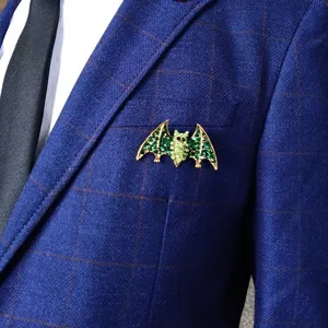 Close-up of a vintage emerald green rhinestone bat brooch pinned on a blue suit lapel