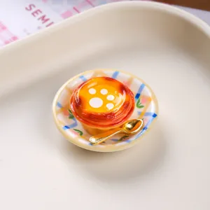 Detailed view of miniature resin egg tart magnet with decorative plate and golden spoon