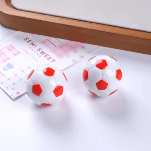 Primo piano di ciondoli a forma di pallone da calcio in resina bianca e rossa per fai da te.