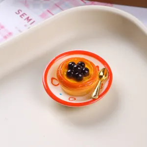 Macro view of a miniature resin egg tart dessert on a plate with a tiny golden spoon