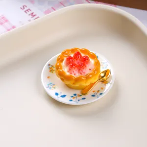 Close-up of realistic strawberry tart resin miniature on a floral ceramic saucer