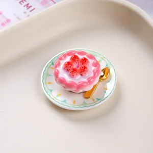 Detailed close-up of a resin miniature strawberry tart on a plate with a gold spoon