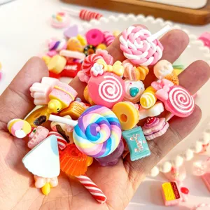 Close-up of colorful resin candy and dessert charms held in a hand