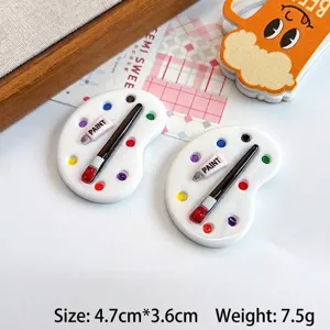 Detailed macro shot of miniature resin paint palette charms with brush and paint tube