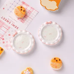 Gros plan d'assiettes miniatures en résine pour maison de poupée avec nœuds roses