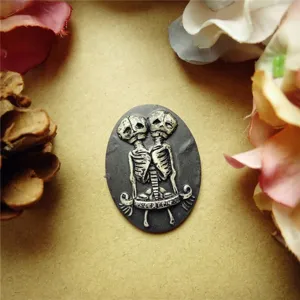 Close-up of a resin relief cabochon featuring conjoined skeleton figures for jewelry making