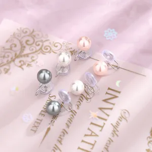 Vista dettagliata di eleganti clip per orecchi con perle tonde bianche e rosa per donne.