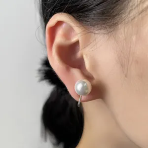 Primo piano di un elegante orecchino a clip con perla grigia tonda per orecchie senza buchi.