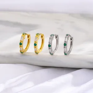 Detalle de pendientes de aro en oro y plata con circonitas esmeralda y transparentes.