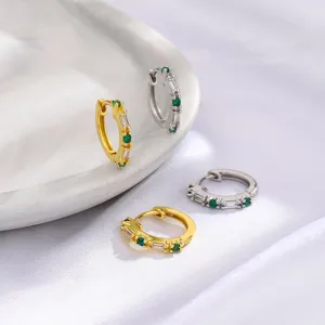 Primer plano de pendientes de aro en oro y plata con circonitas verdes y claras.