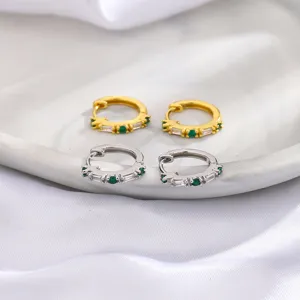 Primer plano de pendientes de aro dorados y plateados con circonitas baguette verdes