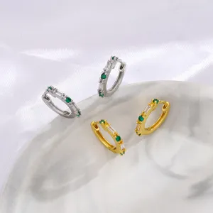 Vista detallada de pendientes de aro dorados y plateados con circonitas verdes y blancas