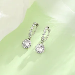 Détail de boucles d'oreilles créoles argentées avec pendentifs ronds en zircone.