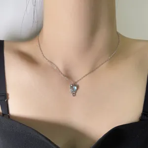 Close-up of a silver cat pendant necklace with a colorful moonstone worn on a neck.
