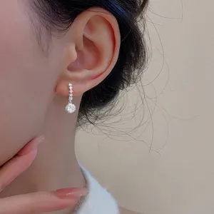 Vue détaillée de boucles d'oreilles pendantes argentées avec pierres de zircon rondes brillantes