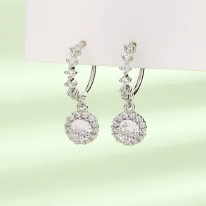 Gros plan d'élégantes boucles d'oreilles pendantes en zircone ronde avec fermoir pavé