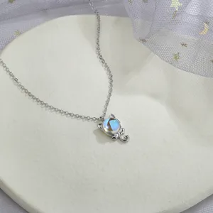 Close-up detail of a silver cat pendant necklace with a colorful moonstone