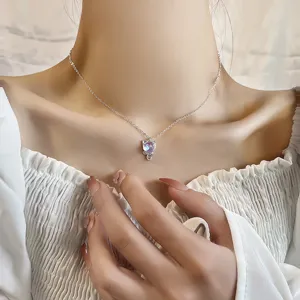 Close-up of a cute silver cat necklace with iridescent moonstone on a woman's neck