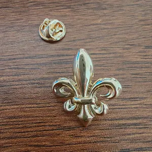Close-up of a polished golden fleur-de-lis lapel pin and its butterfly clutch back