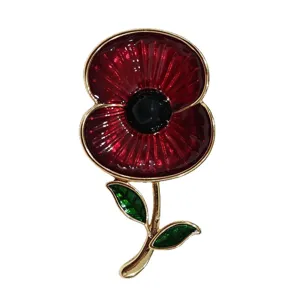 Close-up of red poppy enamel brooch with vibrant red petals and green leaves