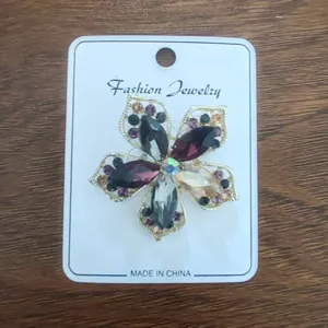 Close-up of a vintage alloy flower brooch with colorful rhinestones on white card