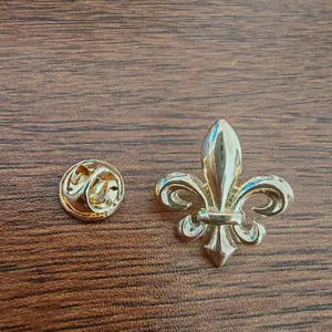 Detailed macro shot of a golden Fleur-de-lis lapel pin and clutch back on wood