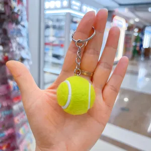 Primer plano de un mini llavero de pelota de tenis en una mano abierta.