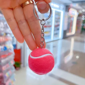 Vista detallada de un mini llavero de pelota de tenis rosa que muestra la textura de fieltro