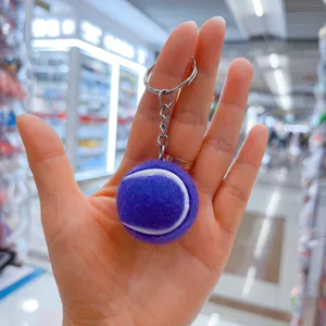 Primer plano de un llavero de pelota de tenis morada y suave sostenido en la mano.