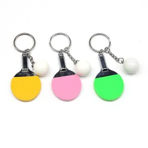 Detailweergave van mini pingpongracket-sleutelhangers in geel, roze en groen met ballen.