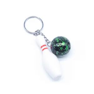 Detail van een sportieve bowling sleutelhanger met een witte kegel en groene bal.