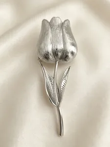 Primo piano di un'elegante spilla a tulipano in argento su morbido tessuto di seta.