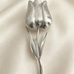 Elegante spilla a forma di tulipano argento per cappotti su fondo in raso bianco.