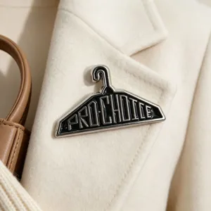 Detailansicht einer Pro-Choice Emaille-Brosche in Kleiderbügelform auf einem Mantel