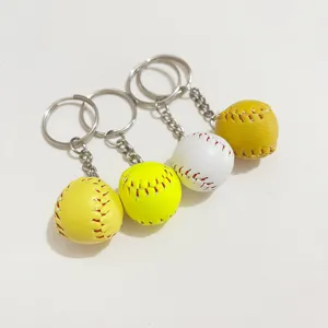 Close-up of mini baseball keychains in white and yellow with red stitching detail.