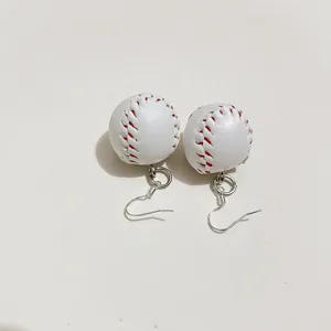 Detailed close-up of white baseball-themed drop earrings with red stitching and silver hooks