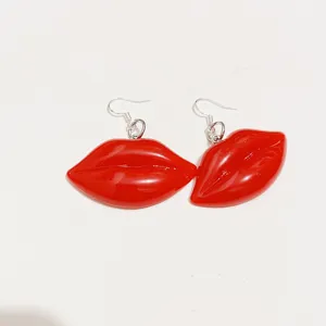 Macro view of glossy red resin lip shaped earrings with silver hooks for a bold look