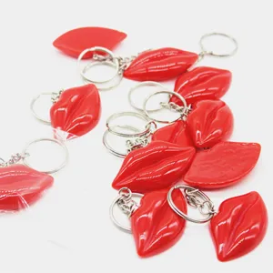 Multiple shiny red resin lip-shaped keychains with silver metal split rings detail