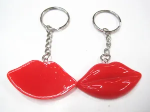 Detail view of two shiny red resin lip keychains with metal rings on white background
