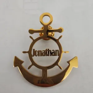 Close-up of a gold stainless steel anchor and ship wheel brooch featuring custom name Jonathan