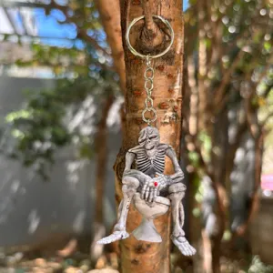 Detail of creative skeleton sitting on toilet keychain hanging on a tree trunk