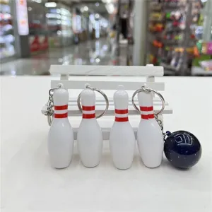 Detailopname van witte bowlingpin-sleutelhangers en een blauwe glitter bowlingbal.