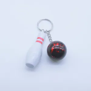 Close-up detail of mini bowling pin and ball keychain featuring red splatter design