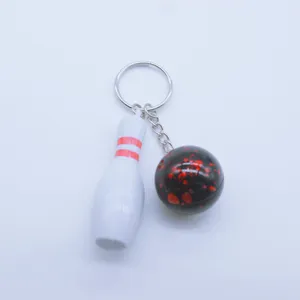Detailed macro view of a miniature bowling pin and ball keychain pendant with ring