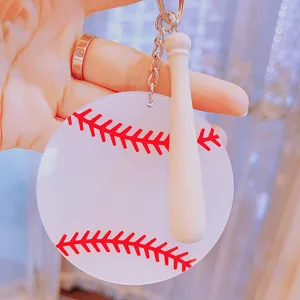 Detailed view of white acrylic baseball keychain with red stitching and mini wooden bat