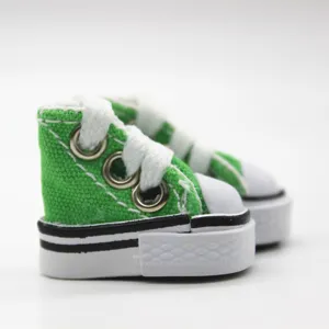 Detail view of 3.5cm mini green canvas doll shoes with white laces and stitching.