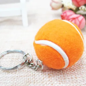 Primer plano detallado de un llavero de pelota de tenis naranja con anilla metálica