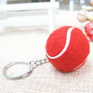 Primer plano de un mini llavero de pelota de tenis roja con textura de fieltro